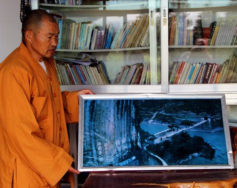 Monk showing picture of the old Jihong Bridge.